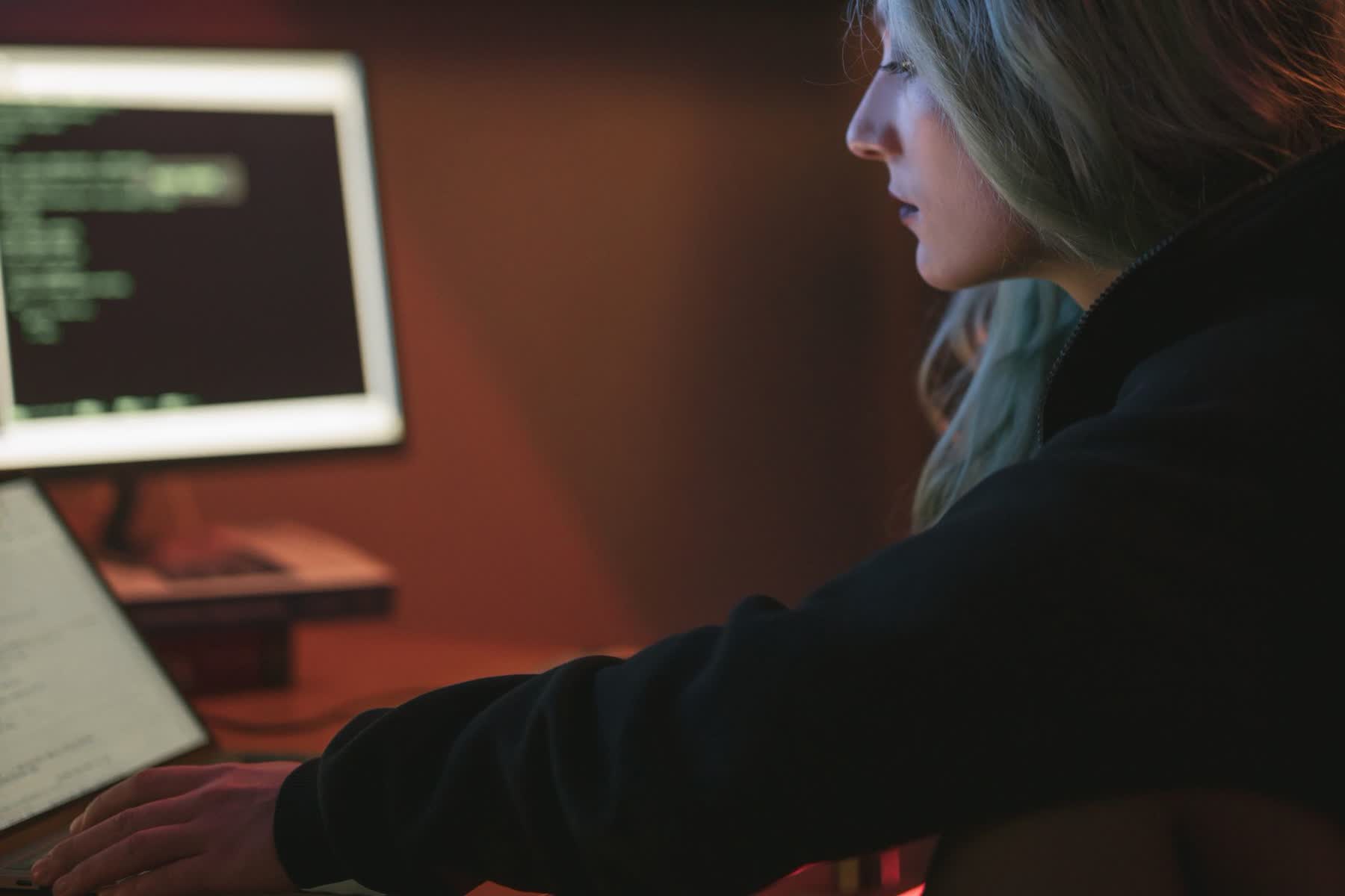 Mulher trabalhando à noite num laptop com código na tela